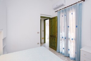 Une chambre à coucher avec un lit, une porte en bois et une fenêtre avec des rideaux.