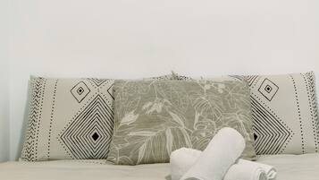 Una cama con almohadas estampadas y toallas enrolladas.
