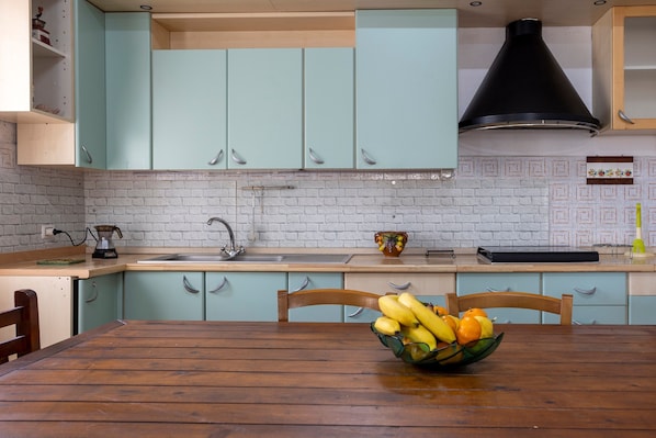 A kitchen with light blue cabinets, a wooden table, and a fruit bowl.