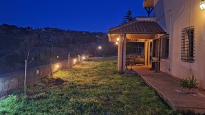 A house with a covered patio, a fenced garden, and a view of a hillside.