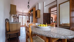 A kitchen with a granite countertop, wooden chairs, a dining table, and a large mirror.
