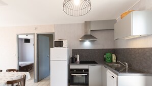 A compact kitchen with a microwave, oven, and sink. - Holiday Home "Ombre d'Été" with Private Garden & A/C (RUOMS)