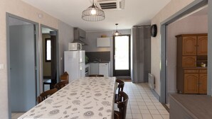 A compact kitchen with a dining area, a microwave, a sink, and cabinets. - Holiday Home "Ombre d'Été" with Private Garden & A/C (RUOMS)