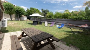 A backyard with a picnic table, a hammock, and two lawn chairs. - Holiday Home "Ombre d'Été" with Private Garden & A/C (RUOMS)