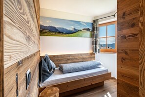 Een houten bank met een matras, een landschapsschilderij en een raam met uitzicht.