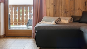 Une pièce avec un canapé, un mur en bois, une porte en verre et une vue sur un balcon.