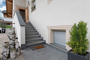 A staircase leading to a door, a potted plant, and a window with blinds.