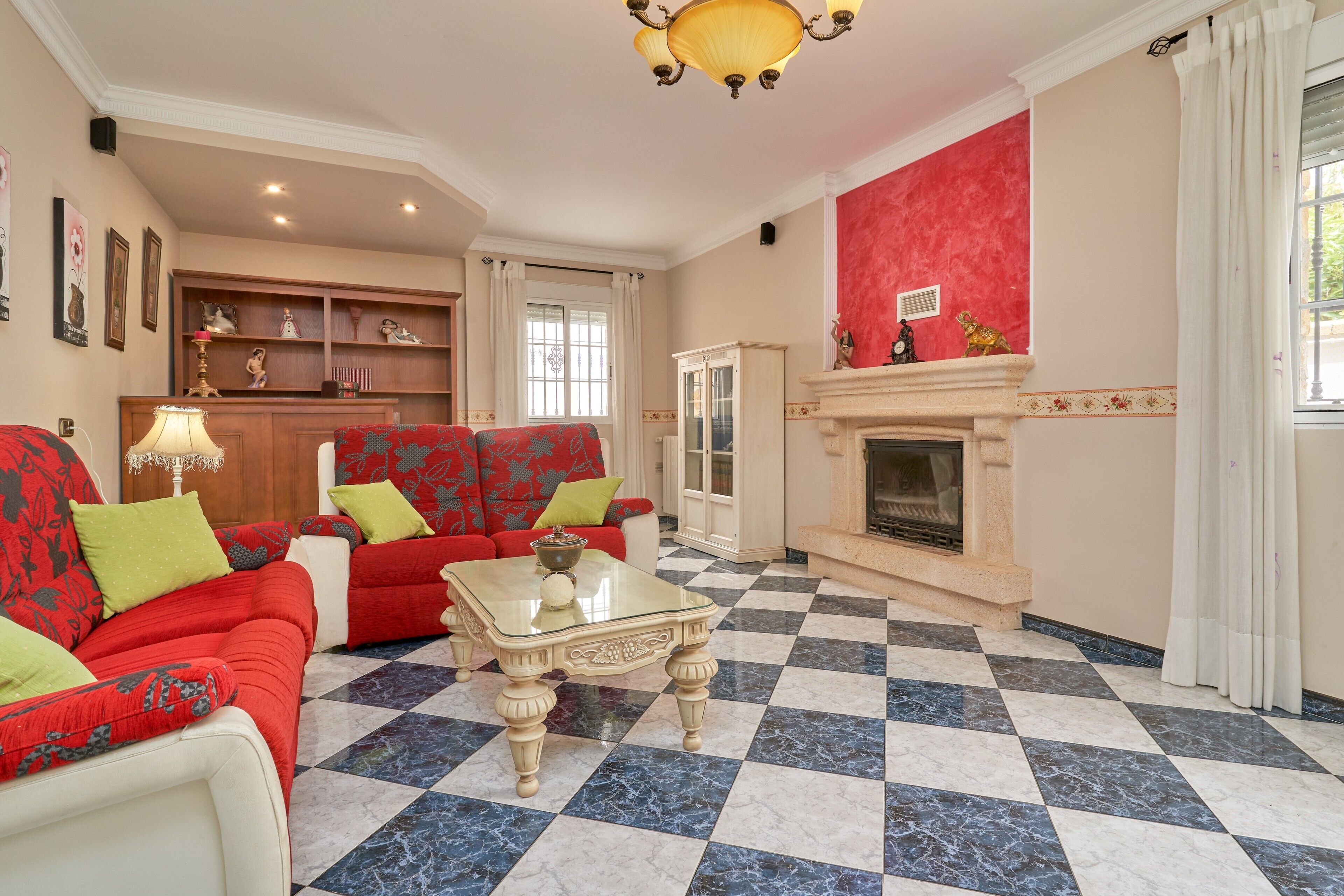 Una sala de estar con piso a cuadros, una chimenea y un juego de sofá rojo y blanco.