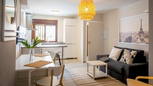 Una sala de estar moderna con comedor, un sofá, una mesa de centro y una lámpara colgante.