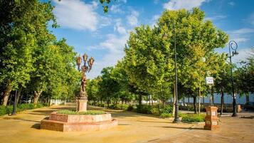 Un parque con una estatua, árboles y un camino pavimentado.