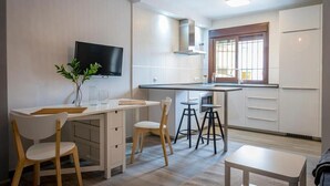 Una cocina moderna con televisor, taburetes de bar y comedor.