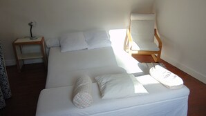 Una habitación sencilla y limpia con cama, una silla y una mesita.