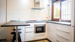 Une cuisine équipée d’un four encastré, d’une hotte en acier inoxydable et d’une fenêtre offrant une vue agréable.