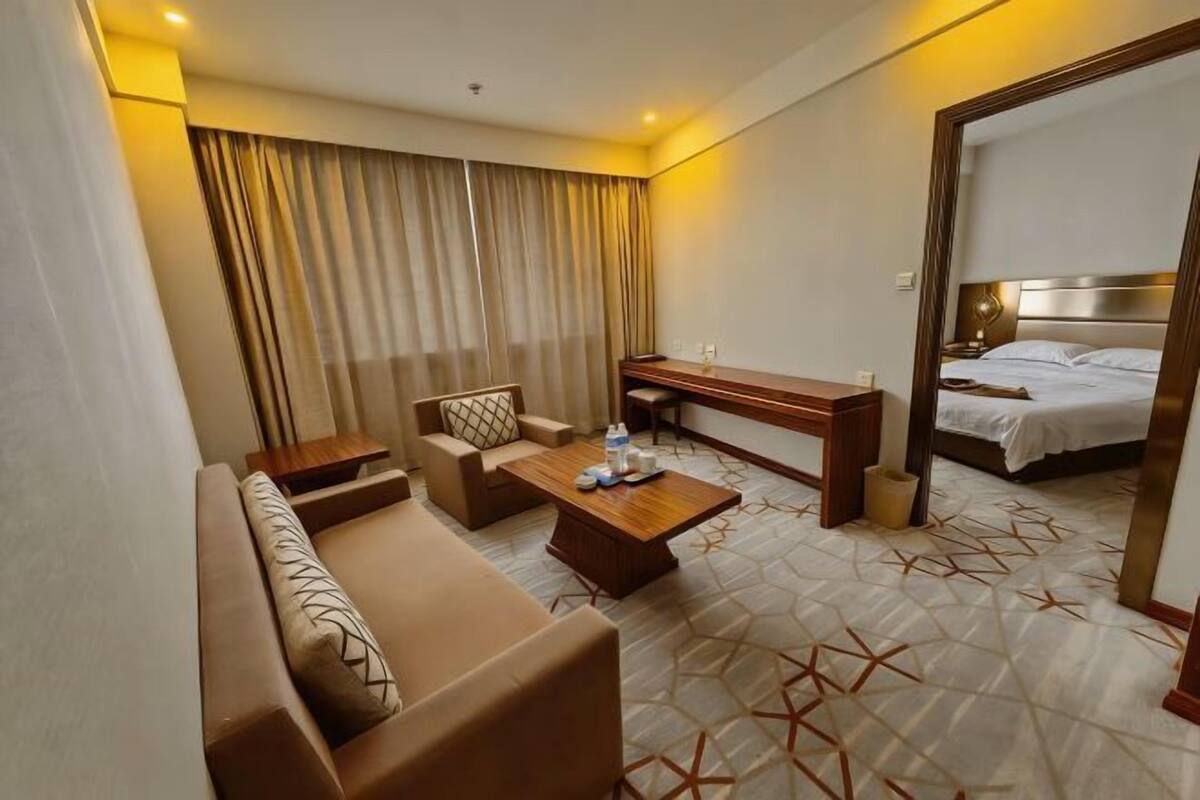 Una habitación de hotel con sofá, mesa de centro, escritorio, cama y un espejo grande.