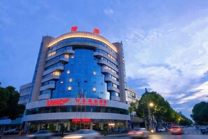 Un hotel de varios pisos con fachada curva, ventanas amplias y señalización llamativa.