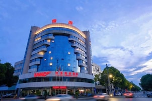 Un hotel de varios pisos con fachada curva, ventanas amplias y señalización llamativa.