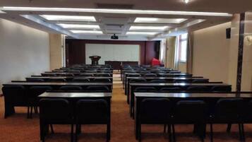 A conference room with rows of tables and chairs, a projector screen, and a podium.