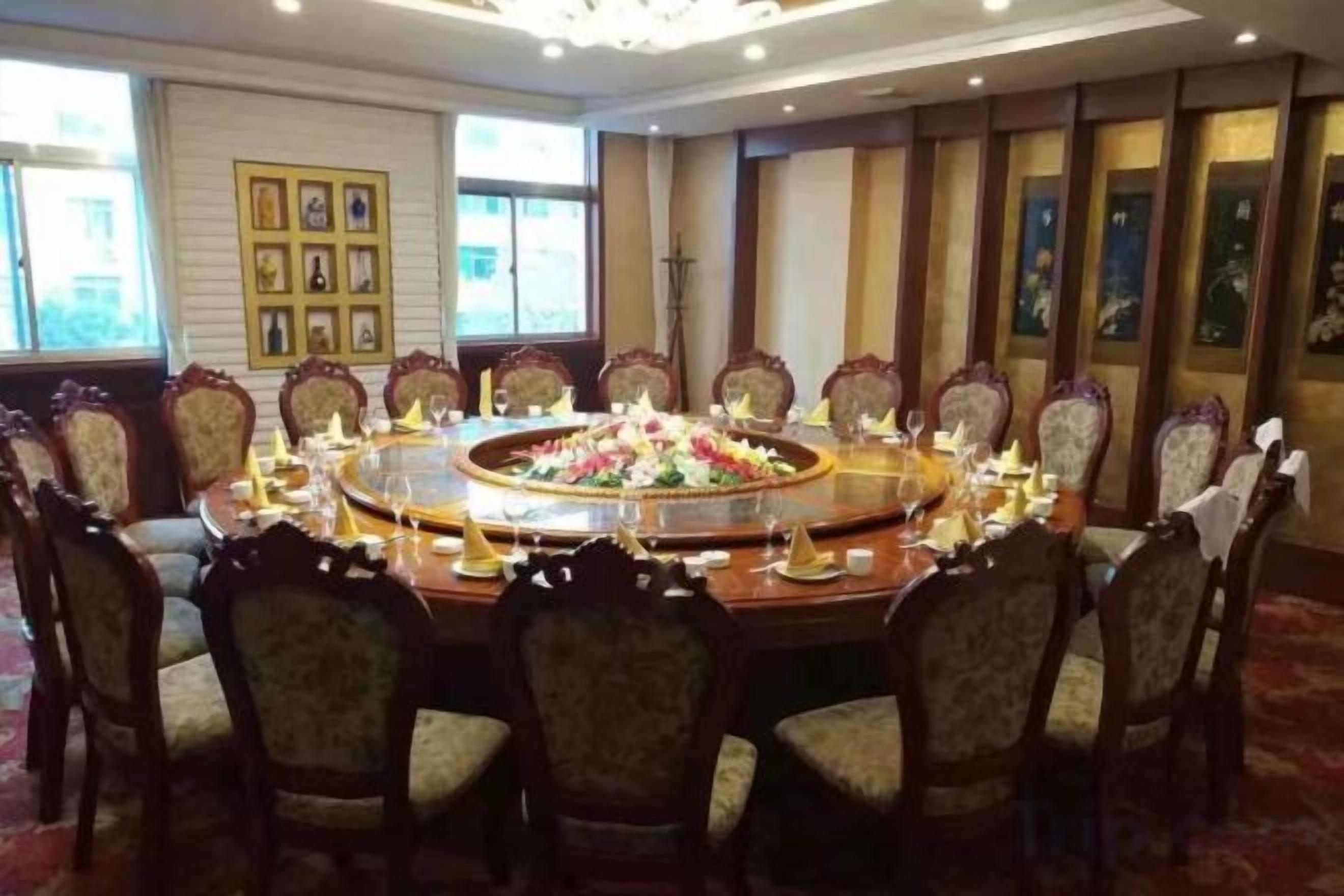 A conference room with a round table, chairs, and a floral centerpiece.