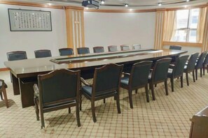 Un salón de conferencias con una larga mesa, sillas, un proyector y una obra de arte enmarcada en la pared.