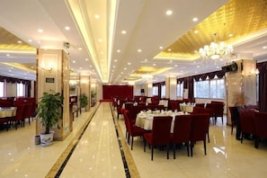 A spacious restaurant with multiple tables and chairs, a polished floor, and a chandelier. - Liaoyuan Business Hotel (Chenggu)