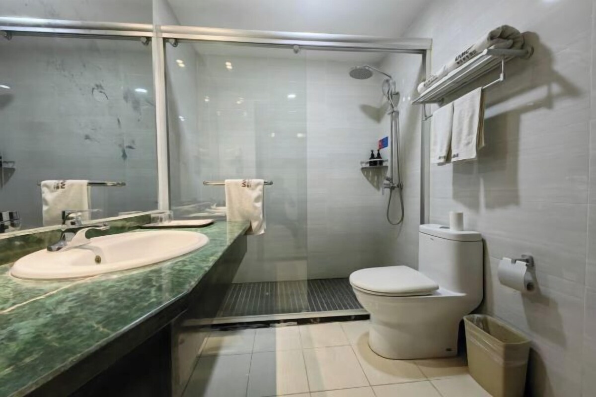 A bathroom with a glass-enclosed shower, a white sink, and a toilet.