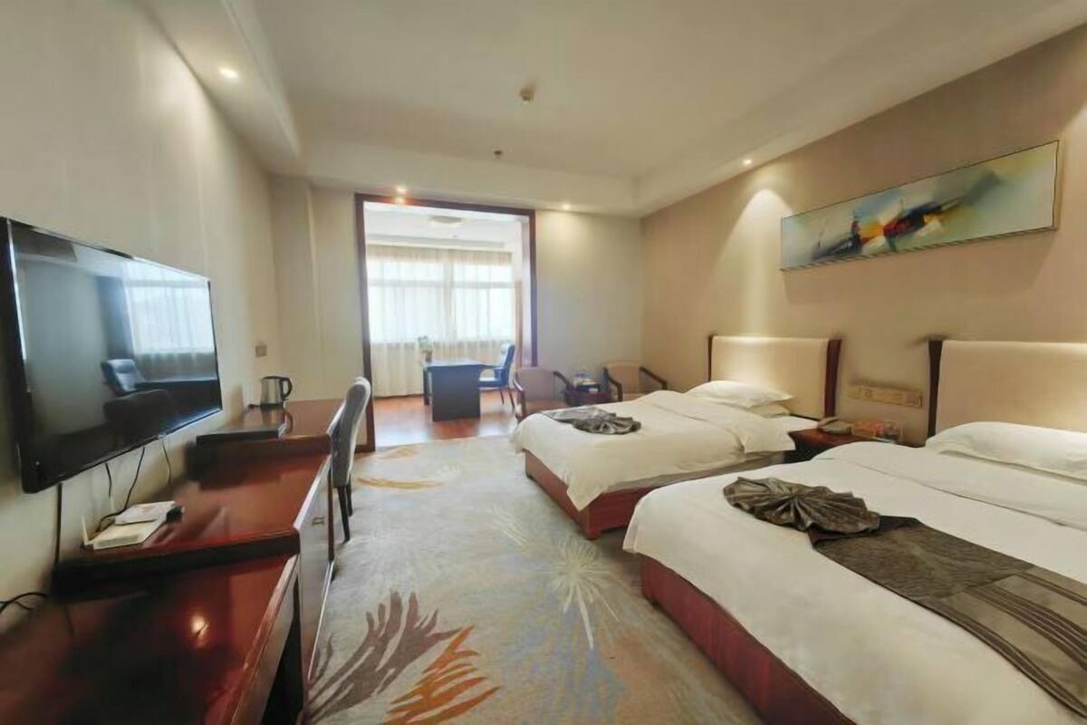 Habitación de hotel con televisión, dos camas, escritorio y una silla.