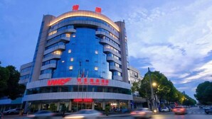 A multi-story hotel with a curved facade, large windows, and a prominent red sign on the ground floor.