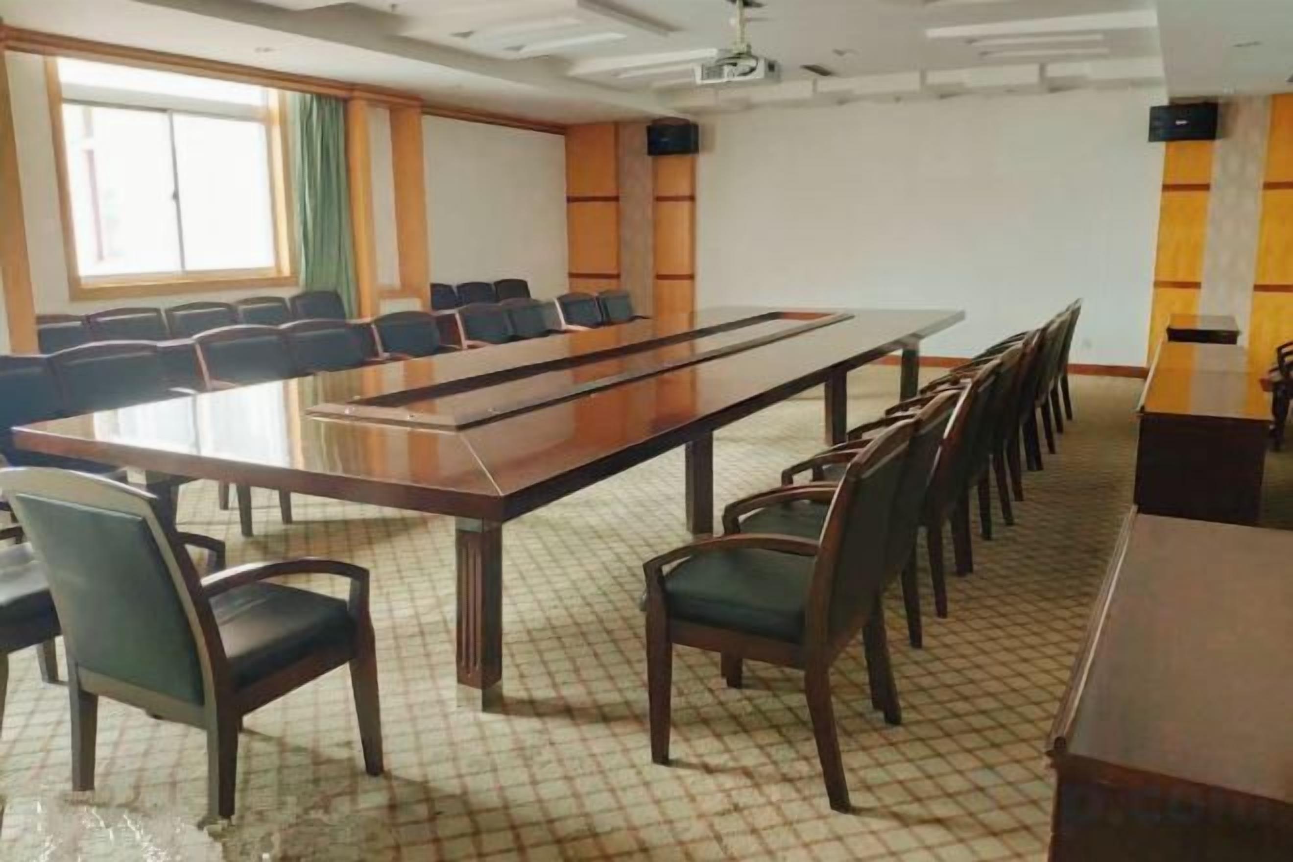 Een vergaderzaal met een lange tafel, stoelen en een projectorscherm.