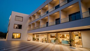 A modern hotel with multiple balconies, large windows, and a spacious outdoor area with potted plants. - Pride Resort Ranakpur. (Desuri)