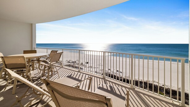 Een balkon met uitzicht op strand en zee.