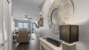A modern living room with a large round mirror, a sofa, and a dining area in the background. - Phoenix VII 1111 by Liquid Life (Orange Beach)