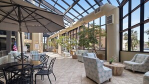 A spacious indoor patio with seating areas, a table, and a flag. - Phoenix VII 1111 by Liquid Life (Orange Beach)