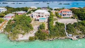 A large, multi-story house with a swimming pool, surrounded by lush greenery and a clear view of the ocean. - Private Pool & Stunning Sunsets Near Chalk Sound (Providenciales)