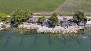 An aerial view of a lakeside property with houses, a dock, and a stone wall. - Cozy 3 Bedroom Lakefront Cottage (Blenheim)
