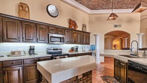 A kitchen with dark wooden cabinets, a white countertop, a brick backsplash, and a large island.