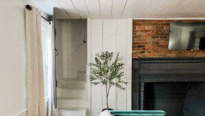 Un salon avec un canapé vert, une cheminée et un escalier menant à une autre pièce.