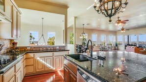 A spacious kitchen with a large island, wooden cabinets, and a view to the outside.