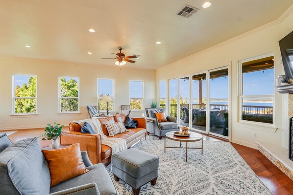 A spacious living room with a large window overlooking a scenic view, a ceiling fan, and a fireplace.