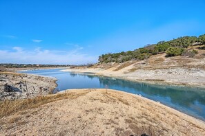 Paesaggio arido e roccioso con cielo azzurro intenso e una distesa d'acqua.