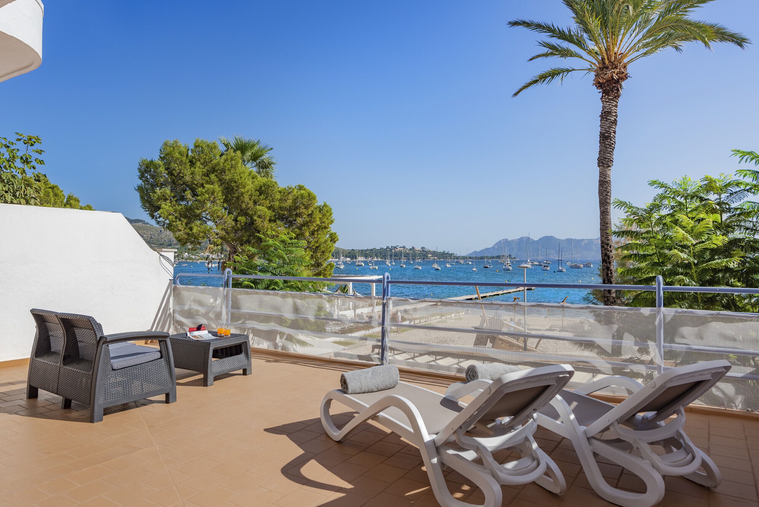 A balcony with two lounge chairs, a small table, and a white tent.