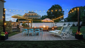 Une terrasse extérieure équipée d’un barbecue, d’une table à manger, de chaises et de parasols.