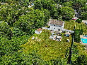 Une vue aérienne d’une maison dotée d’un grand jardin, d’une piscine et d’une pelouse bien entretenue.