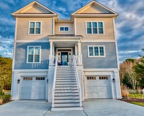 A two-story house with a central entrance, a staircase, and two garages. - Tidal Walk * New 5BR Bethany Beach House (Millville)