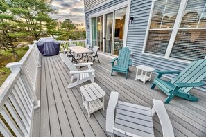 A wooden deck with outdoor furniture, including chairs and a table, and a covered grill area. - Tidal Walk * New 5BR Bethany Beach House (Millville)