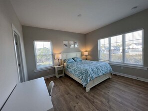 A bedroom with a bed, bedside tables, a desk, and large windows. - Tidal Walk * New 5BR Bethany Beach House (Millville)