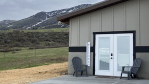 Un bâtiment sur lequel on peut lire l’inscription « BIENVENUE », deux fauteuils Adirondack et une vue sur une montagne enneigée.