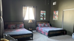 Une chambre avec deux lits, une fenêtre avec des rideaux, une lampe et deux affiches au mur.