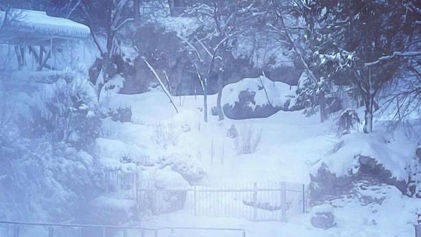 Une source thermale où l’on peut se baigner, entourée d’arbres couverts de neige et bordée d’une terrasse en bois.