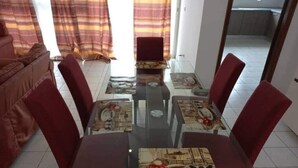 A dining area with a glass-top table, red upholstered chairs, and patterned tablecloths. - Magnifique Appartement Meublé Avec Piscine à Pointe Noire (Pointe-Noire)