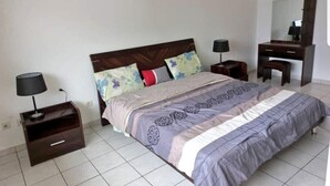 A bedroom with a bed, nightstands, a dresser, and a mirror. - Magnifique Appartement Meublé Avec Piscine à Pointe Noire (Pointe-Noire)